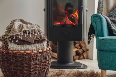 A blanket basket and an armchair in front of a log fire