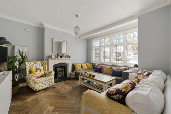 Elegant living room with bay window, wood-burning stove, herringbone flooring and stylish modern décor.