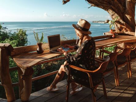 Person with a laptop on a beachfront balcony