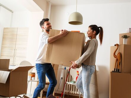 Couple carrying boxes into new home