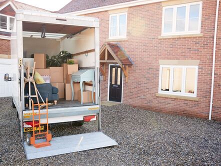 A moving van full of cardboard boxes outside a house