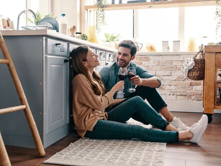 A couple sitting on the kitchen floor with a glass of wine